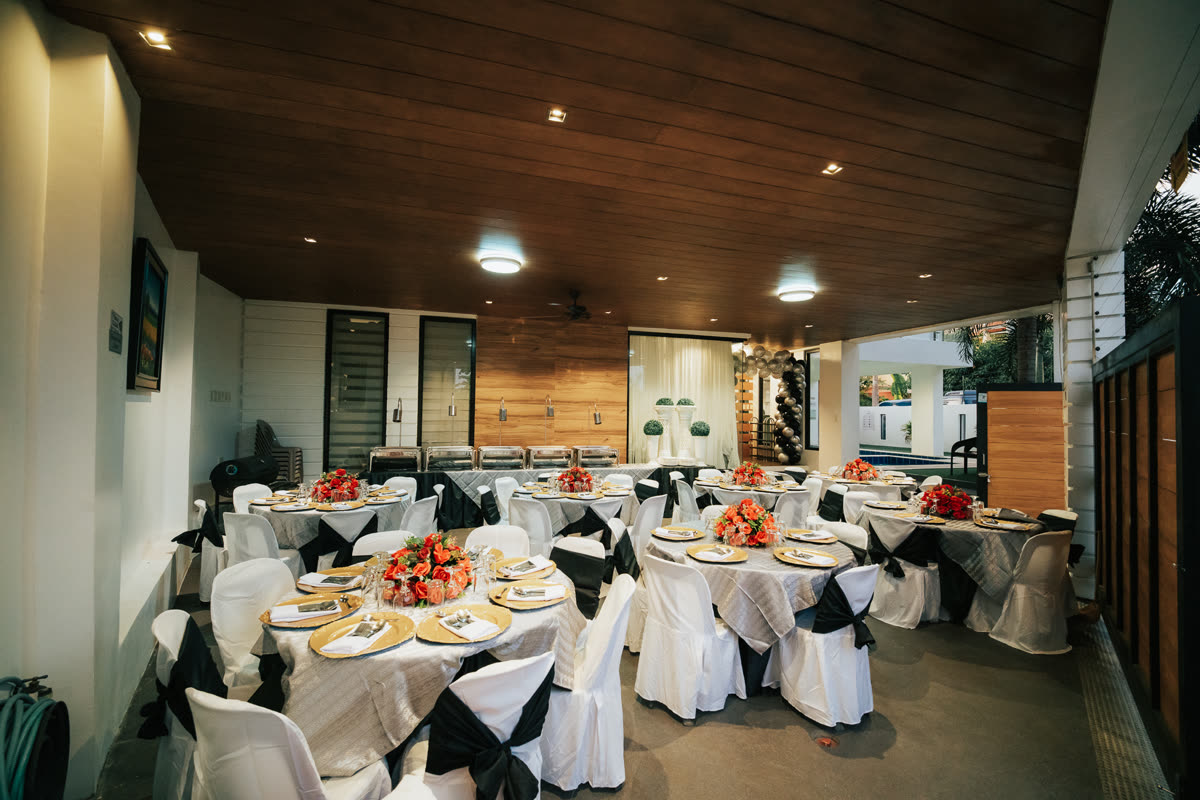 A covered lanai laid out for a celebration — round tables, linen and flowers